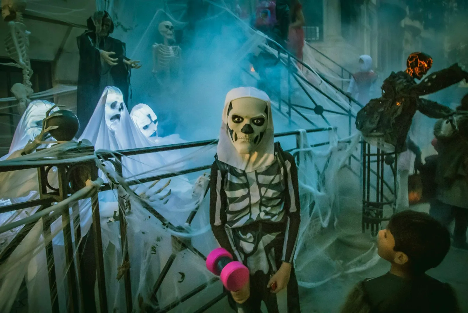 Niño disfrazado de esqueleto junto a decoraciones de fantasmas
